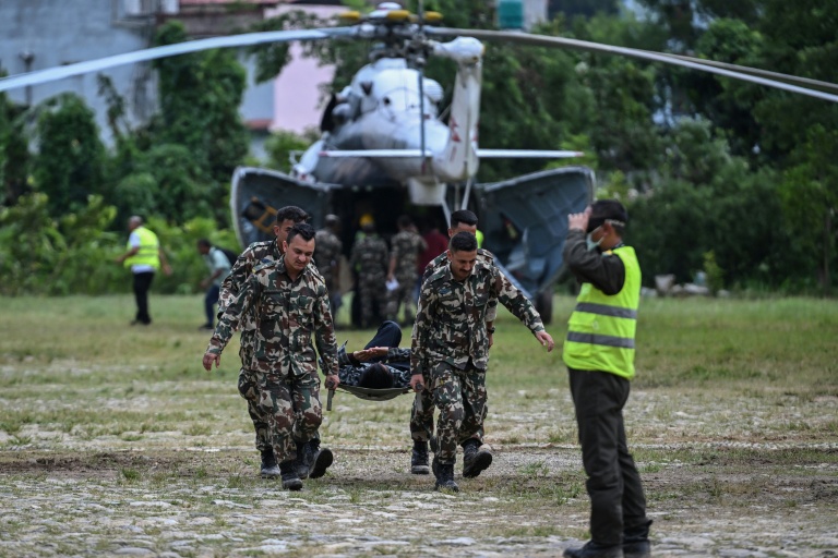 Des militaires transportent un blessé sur une civière lors des opérations de secours après la crue destructrice qui a fait plus de 600 morts à la frontière entre le Népal et la Chine, le 29 août 2026 à Trishuli, dans le district népalais de Nuwakot 