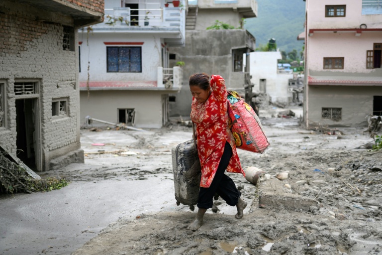 Une femme transporte des effets personnels qu'elle a pu sauver après la crue destructrice qui a fait au moins 633 morts à la frontière entre le Népal et la Chine, le 28 août 2026 dans le district népalais de Nuwakot  