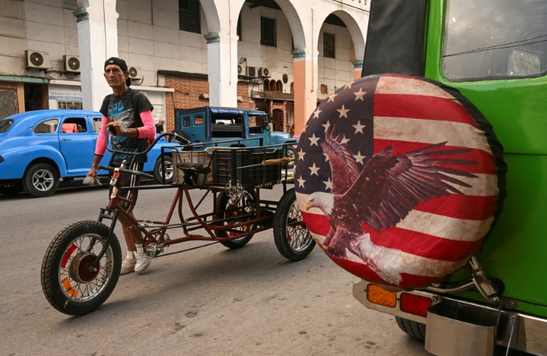 Un homme pousse un vélo devant une jeep arborant une housse de roue ornée d’une image inspirée du drapeau américain, à La Havane, la capitale cubaine, le 23 janvier 2026.