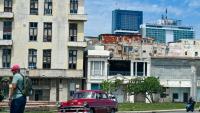Un homme marche dans la rue tandis qu'une voiture classique passe, avec en arrière-plan l'hôtel Iberostar Selection et l'hôtel Habana Libre Melia, à La Havane, le 2 juin 2026