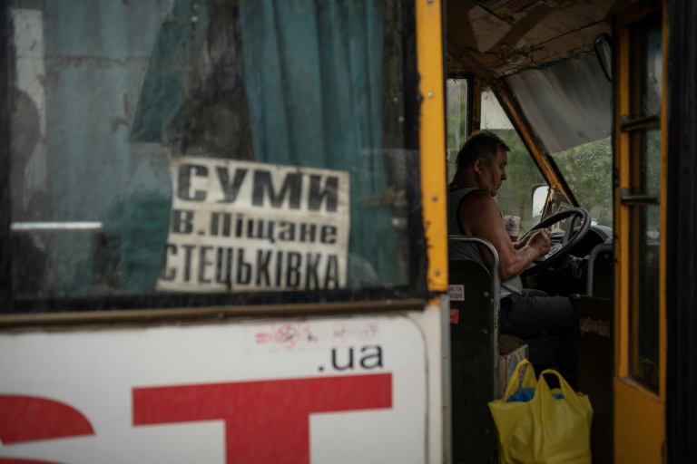 Un chauffeur de bus attend des passagers dans la localité de Stetskivka, proche de la ligne de front, dans le nord-est de l'Ukraine, le 12 juin 2025