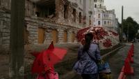 Une mère et sa fille passent près d'un bâtiment détruit par un bombardement russe, le 12 juin 2025 à Soumy, dans le nord-est de l'Ukraine 