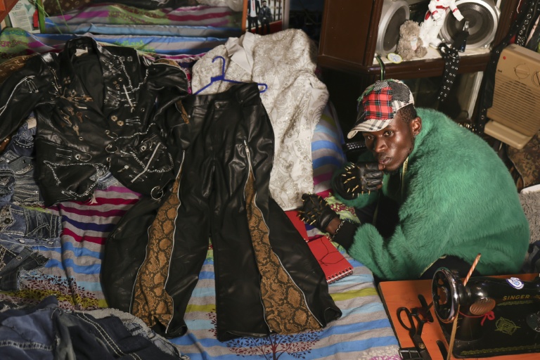 Le créateur de mode Morgan Azedy et quelques-unes de ses créations fabriquées à partir de tissus récupérés sur des marchés de vêtements d'occasion et des décharges, dans son atelier de Nairobi, le 6 octobre 2025 au Kenya