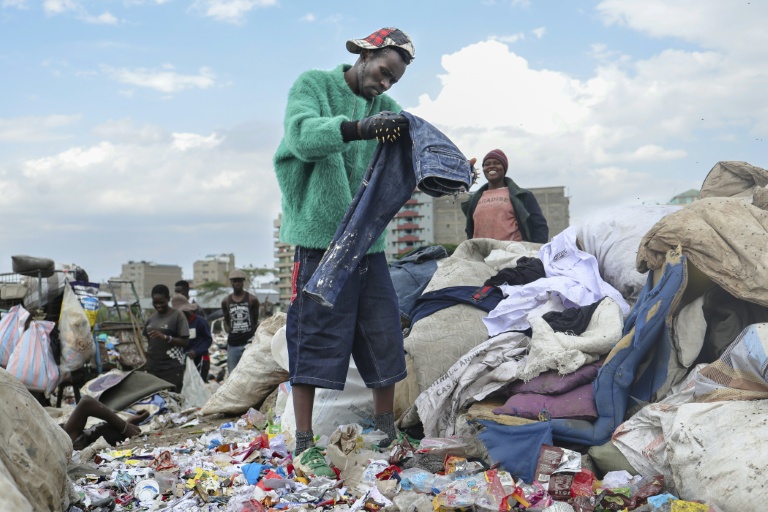 Le créateur de mode Morgan Azedy fouille dans des piles de vêtements mis au rebut dans une décharge à Nairobi, le 6 octobre 2025 au Kenya