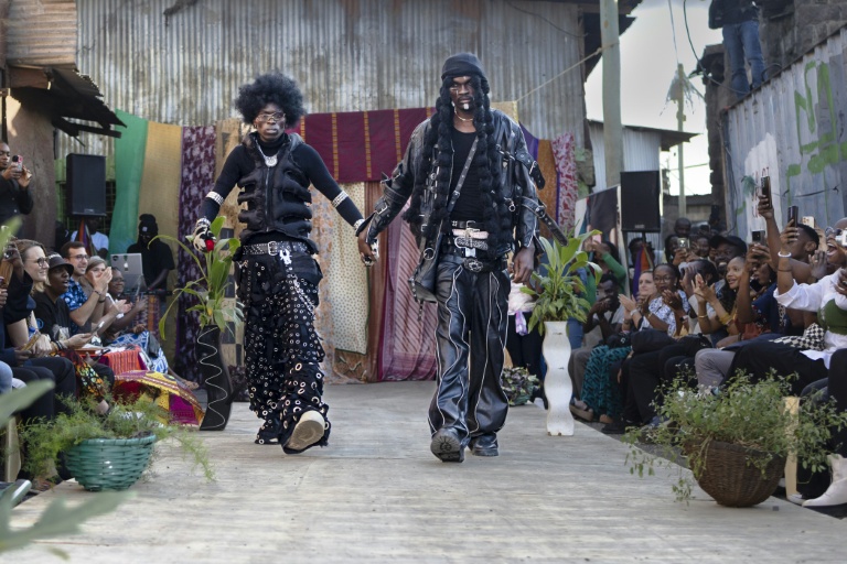 Le styliste Morgan Azedy présente avec un mannequin les tenues qu'il a créées à partir de tissus et de vêtements mis au rebut, lors du défilé de mode Gikomba Runway Edition à Nairobi, le 10 octobre 2025 au Kenya
