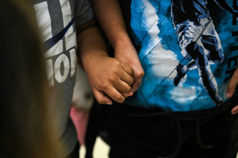 Deux enfants américains se tiennent le main à l'aéroport international de Miami avant de se rendre au Guatemala, le 4 décembre 2025 