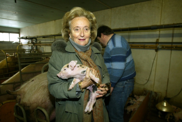Bernadette Chirac tient un porcelet dans ses bras lors de la visite d'une exploitation agricole à Sarran, en Corrèze, le 8 mars 2004 
