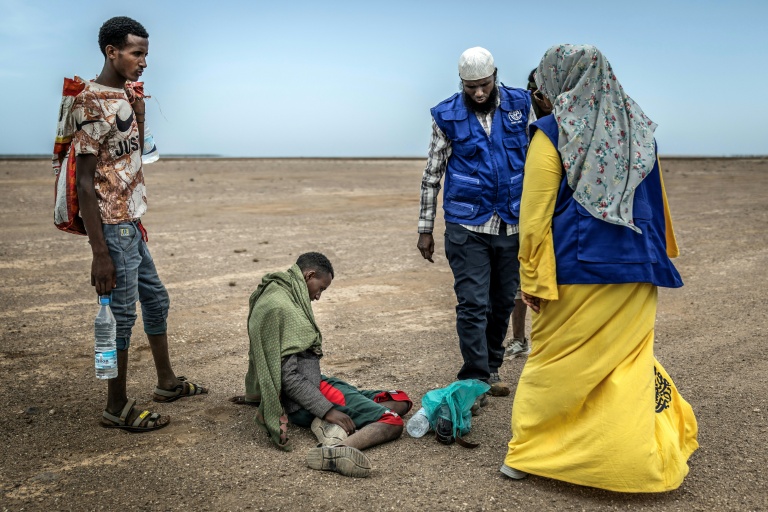 Des membres de l'OIM viennent en aide dans une zone désertique à un migrant épuisé, le 12 avril 2026, près d'Obock, à Djibouti