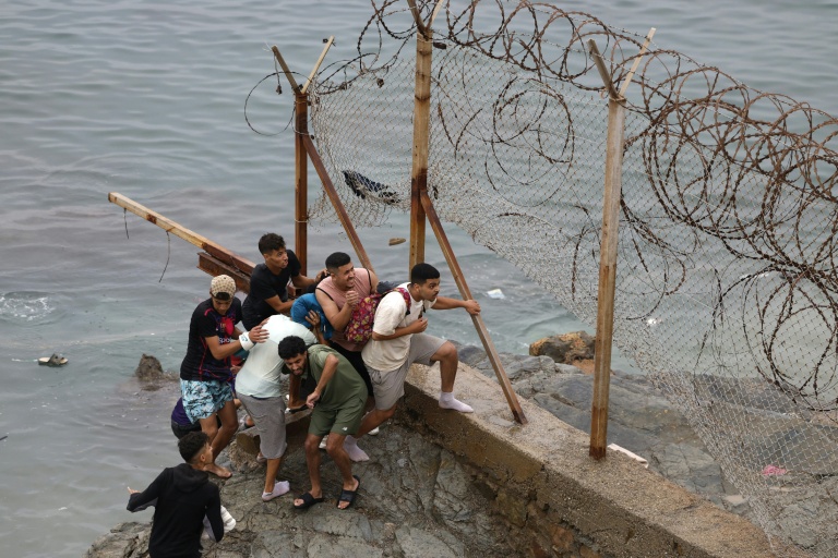 Des hommes se rassemblent le long d'une clôture près de la ville marocaine de Fnideq, située à la frontière avec l'enclave espagnole Ceuta, le 31 juillet 2026
