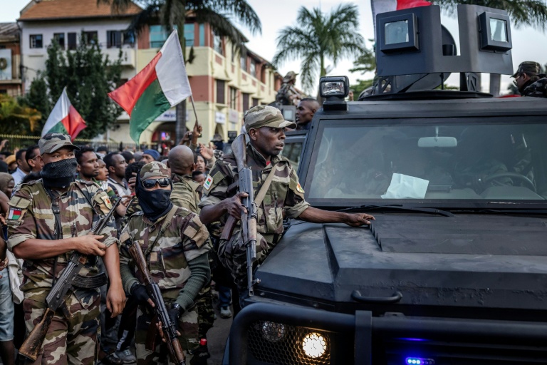 Des soldats malgaches en véhicules blindés sont entourés de manifestants saluant leur arrivée à l'hôtel de ville d'Antananarivo, le 11 octobre 2025