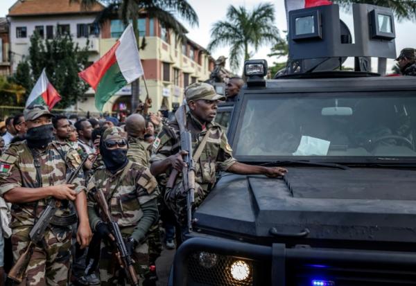 Des soldats malgaches en véhicules blindés sont entourés de manifestants saluant leur arrivée à l'hôtel de ville d'Antananarivo, le 11 octobre 2025