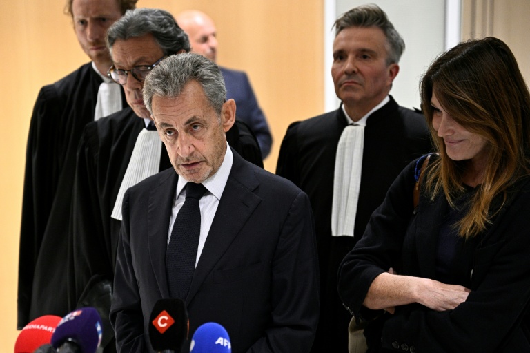 L'ex-président Nicolas Sarkozy (au centre) parle à la presse, accompagné de son épouse Carla Bruni (à droite) et de l'avocat Jean-Michel Darrois (deuxième à gauche) au tribunal à Paris, le 25 septembre 2025