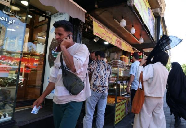Un Iranien parle au téléphone dans une rue de Téhéran le 25 mai 2026