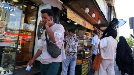 Un Iranien parle au téléphone dans une rue de Téhéran le 25 mai 2026