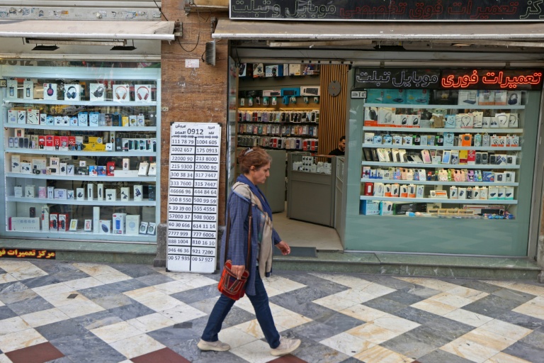 Une Iranienne passe devant une boutique de mobiles à Téhéran le 19 avril 2026