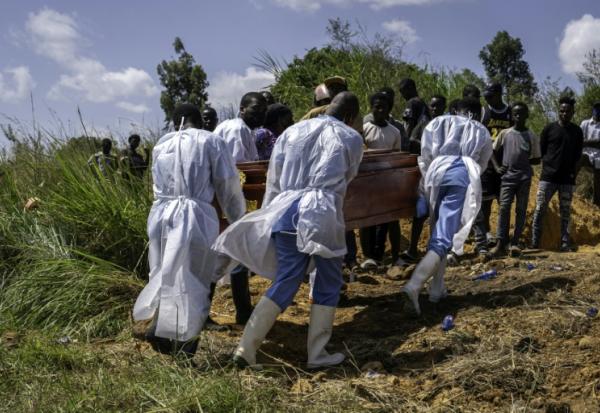 Des agents de santé, équipés de vêtements de protection, transportent vers le cimetière le cercueil d'une personnes suspectée d'avoir succombé à la maladie d'Ebola, à Bunia, dans l'est de la République démocratique du Congo, le 25 mai 2026