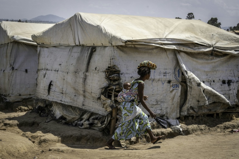 Une femme déplacée, son enfant sur le dos, traverse le camp de Kigonze à Bunia, dans l'est de la République démocratique du Congo, le 28 mai 2026 alors qu'une épidémie d'Ebola touche le pays