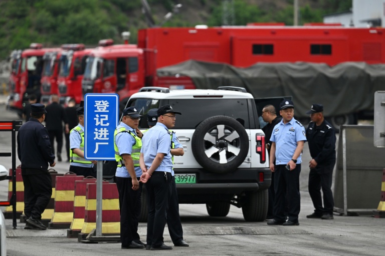 Des policiers devant la route menant à la mine de charbon de Liushenyu, où un coup de grisou dévastateur a fait au moins 82 morts, le 24 mai 2026 dans le district administratif de Qinyuan, dans la province chinoise septentrionale du Shanxi