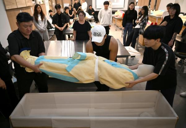 Des étudiants s'entraînent sur un mannequin au rite de  la mise en bière dans une salle de classe de l'Institut des sciences et technologies de Busan, dans le sud-est de la Corée du Sud, le 24 septembre 2025
