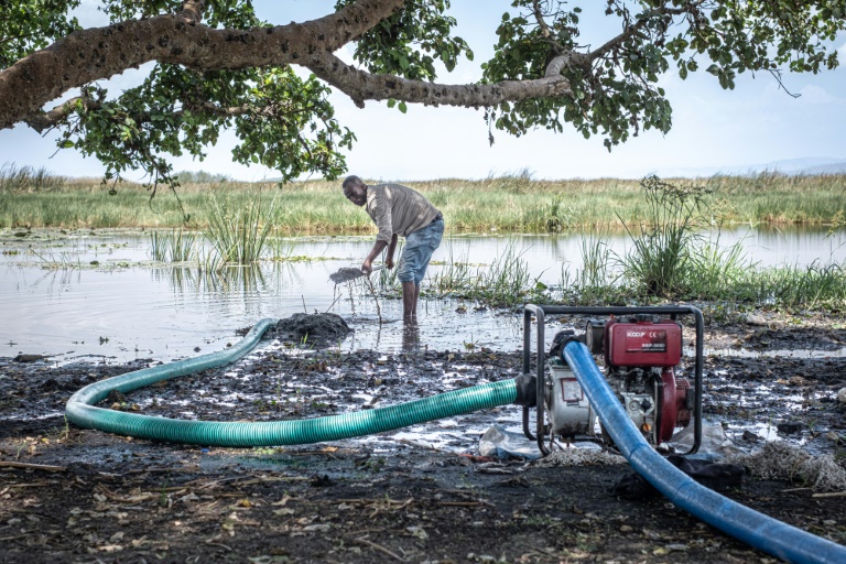 Un homme répare un tuyau relié à un générateur qui pompe l'eau du lac Dembel vers l'un des nombreux champs cultivés le long de ses rives, le 20 mai 2025 à Batu, en Ethiopie