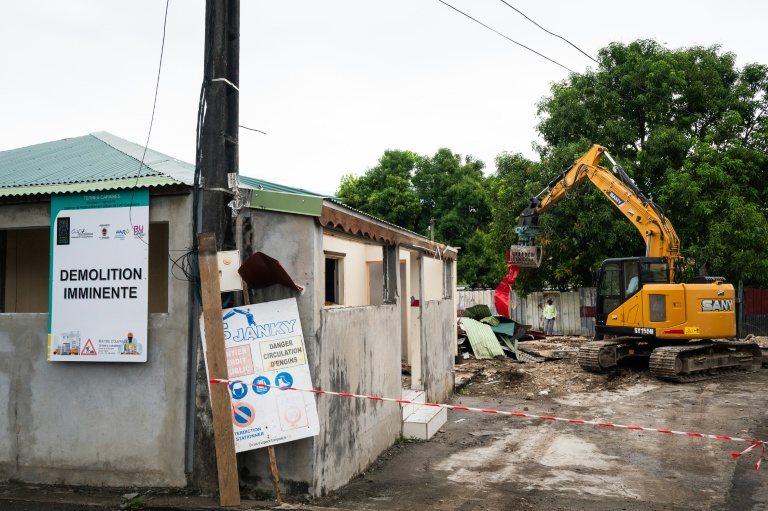 Un engin démantèle un bâtiment dans un quartier des Abymes en Guadeloupe qui doit être reconstruit, le 9 avril 2025