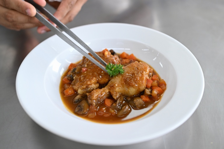 Un élève-cuisinier dresse un poulet sauté chasseur à l'École Ducasse de Gurugram, en Inde, le 22 septembre 2026
