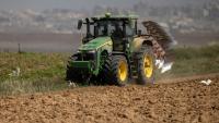 Un agriculteur en tracteur dans un champ agricole près de la frontière entre le sud d'Israël et la bande de Gaza, le 21 mai 2025