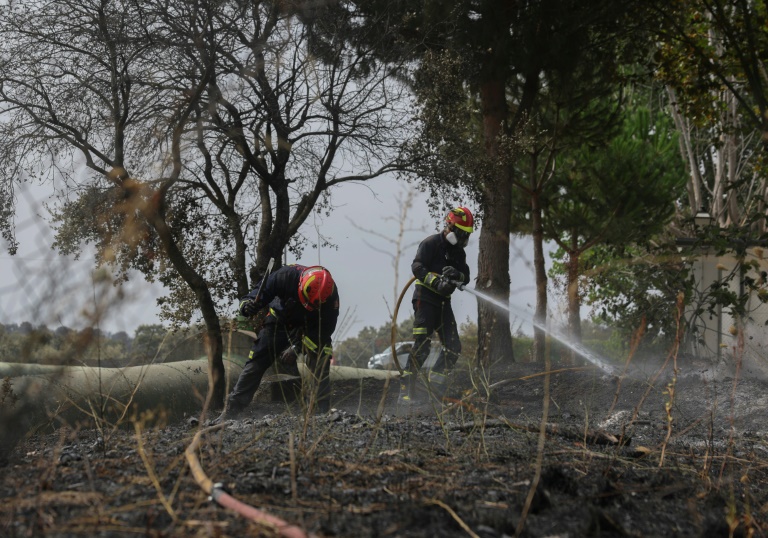 Les pompiers refroidissent le sol à proximité d'une école, à la suite d'un incendie de forêt dans la banlieue de Tres Cantos, au nord de Madrid en Espagne, le 12 août 2025