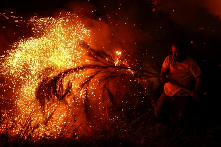 Un homme tente d'éteindre un incendie de forêt à l'aide d'une branche d'arbre à Trancoso, au Portugal, le 12 août 2025