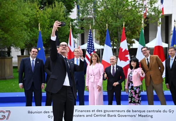 Le ministre de l'Economie Roland Lescure prend un selfie lors de la traditionnelle photo de groupe des ministres des Finances et des gouverneurs des banques centrales du G7, le 18 mai 2026 à Paris