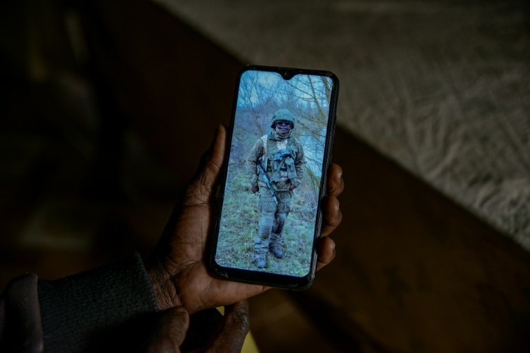 Josephine Ngoya, la mère d'Erastus Mundia, montre une photo de son fils, chez elle à Nabemo au Kenya, le 27 février 2026