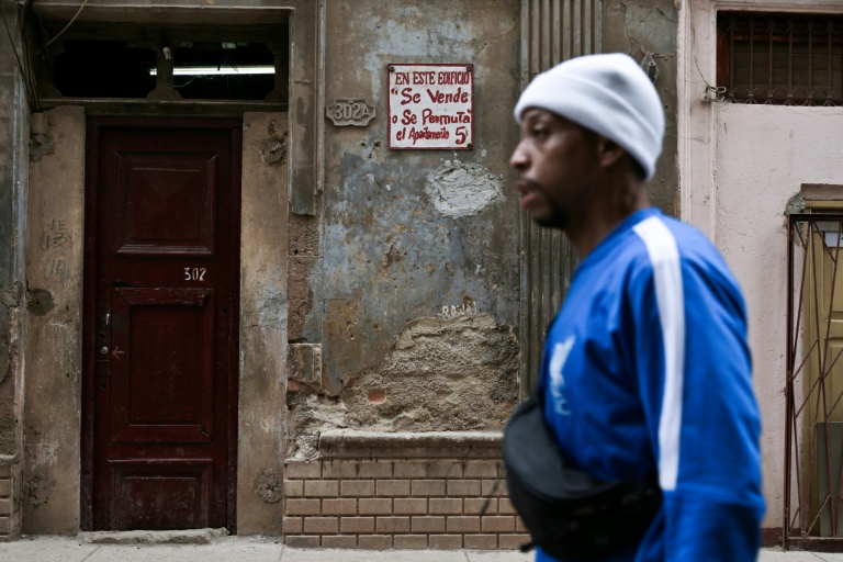 Un homme marche devant un immeuble où un appartement est en vente dans un quartier historique de La Havane, le 23 avril 2026