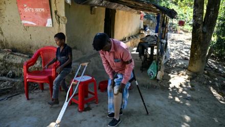 Ali Hossain (à droite), un Bangladais de 40 ans qui a perdu une jambe à cause d’une mine lorsqu'il ramassait du bois, retire sa prothèse devant sa maison dans le district de Bandarban le 19 décembre 2025