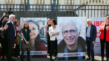 Cécile Kohler (3e G) et Jacques Paris (2e D) devant leurs portraits décrochés des grilles de l'Assemblée nationale, à Paris le 14 avril 2026