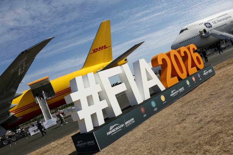 Le logo du salon aéronautique international de Farnborough devant un Boeing 777-200 (g) du géant du transport DHL et un Boeing 747 de GE Aerospace (d), lors de la journée d'ouverture à Farnborough, au sud-ouest de Londres, le 20 juillet 2026
