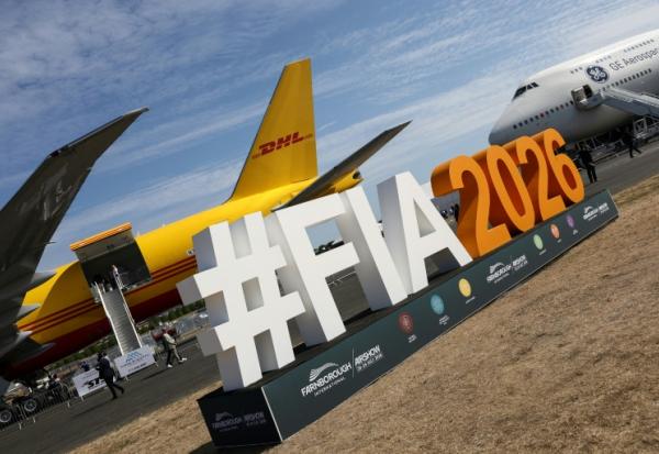 Le logo du salon aéronautique international de Farnborough devant un Boeing 777-200 (g) du géant du transport DHL et un Boeing 747 de GE Aerospace (d), lors de la journée d'ouverture à Farnborough, au sud-ouest de Londres, le 20 juillet 2026