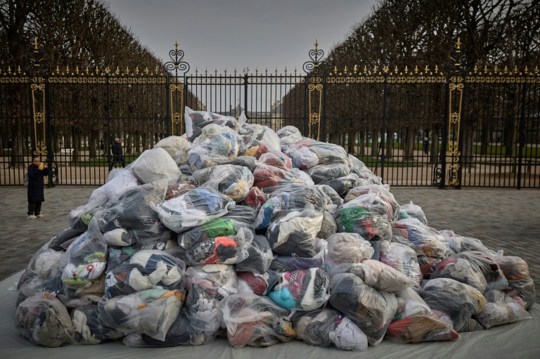 Des sacs de déchets textiles devant la porte du Palais du Luxembourg, où se trouve le Sénat lors d'une manifestation contre la fast-fashion, à Paris, le 14 mars 2025