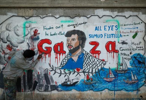 Un artiste peint une fresque dénonçant l'interception par Israël de la flottille pour Gaza, le 19 mai 2026 à Nousseirat, dans le centre de la Bande de Gaza