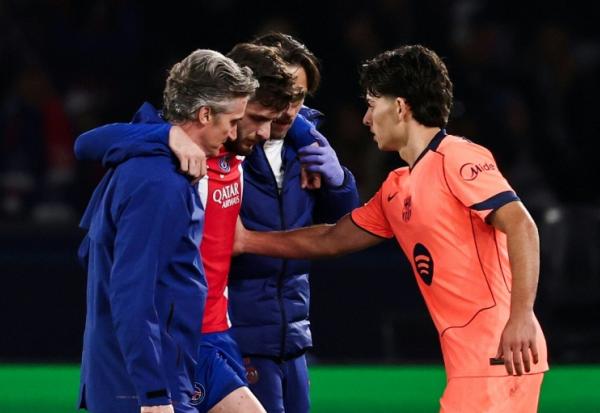 L'attaquant du PSG Khvicha Kvaratskhelia (c) quitte la pelouse après s'être blessé au genou droit lors du match contre le FC Barcelone, réconforté par Xavi Espart, le 20 octobre 2026 au Parc des Princes
