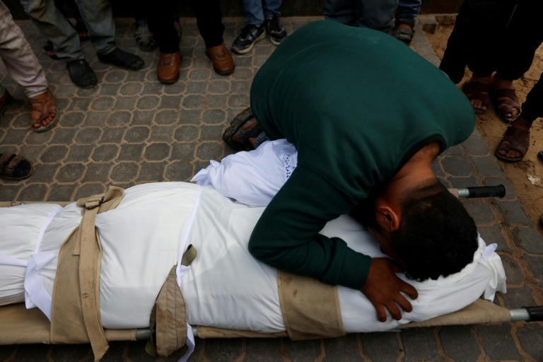 Un homme prosté sur le corps d'une personne tuée dans une frappe israélienne, à l'hôpital Al-Chifa le 4 février 2026