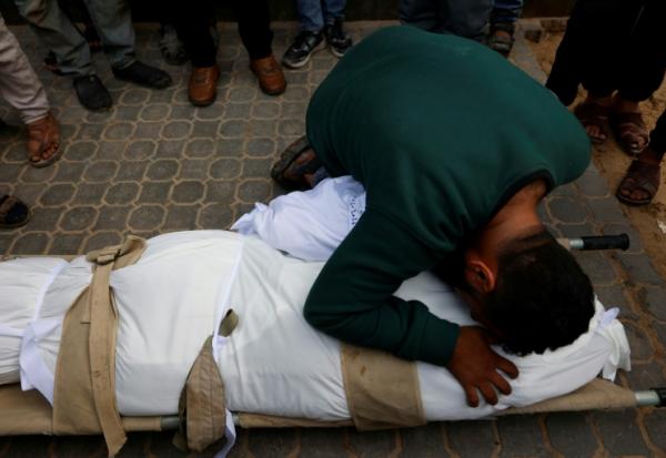 Un homme prosté sur le corps d'une personne tuée dans une frappe israélienne, à l'hôpital Al-Chifa le 4 février 2026