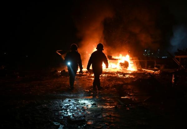Des pompiers luttent contre un incendie provoqué par un bombardement russe sur un entrepôt de la compagnie des postes Nova Pochta dans un village près de Kharkiv, le 13 janvier 2026 en Ukraine