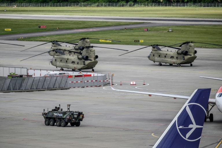 Un véhicule blindé de la police suisse passe devant un hélicoptère de l'armée américaine sur le tarmac de l'aéroport de Genève, le 11 juin 2026 