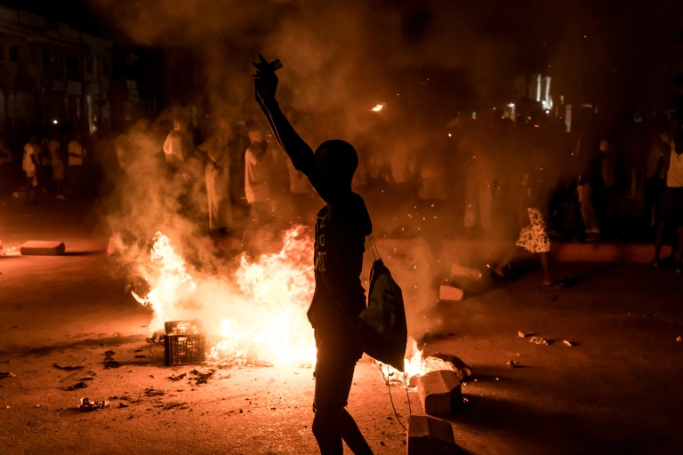 Un manifestant se tient près d'une barricade lors d'un rassemblement spontané à Brusubi en Gambie le 8 septembre 2026, pour protester contre des semaines de coupures d'électricité prolongées dans le pays  
