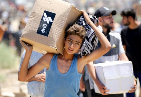 Un garçon porte une boîte d'aide humanitaire de la Fondation humanitaire de Gaza (GHF), venant d'un centre de distribution dans le centre de la bande de Gaza le 29 mai 2025