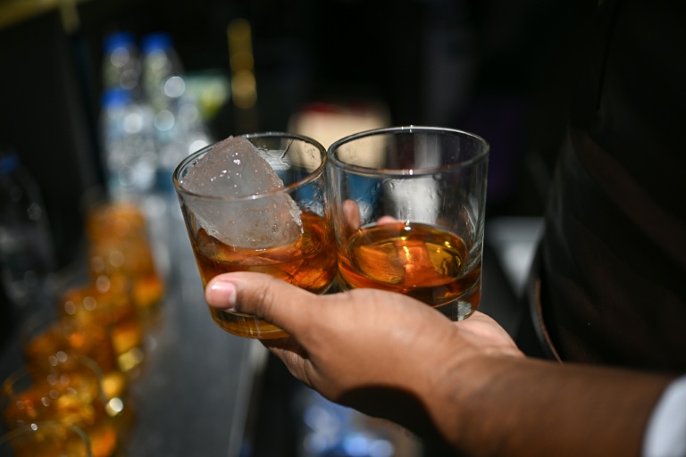 Un barman tient des verres de rhum lors d'un événement organisé par le producteur de rhum Hacienda Santa Teresa, le 13 décembre 2025 à Caracas, au Venezuela
