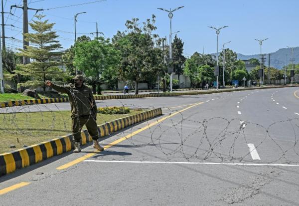 Un agent de sécurité place du fil barbelé sur une route menant à l'hôtel Serena à Islamabad (Pakistan), le 19 avril 2026