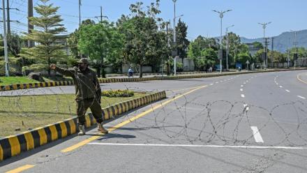Un agent de sécurité place du fil barbelé sur une route menant à l'hôtel Serena à Islamabad (Pakistan), le 19 avril 2026