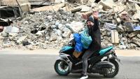 Un homme transportant des effets personnels passe à moto devant des destructions, alors que des habitants libanais regagnent leur quartier dans la banlieue sud de Beyrouth après l’entrée en vigueur, le 17 avril 2026, d’un cessez-le-feu de 10 jours avec Israël.