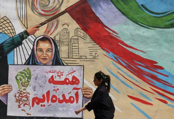 Une Iranienne passe devant une fresque anti-américaine et anti-israélienne sur laquelle on peut lire "Pour la révolution, nous sommes tous venus", dans la capitale Téhéran, le 10 mai 2026